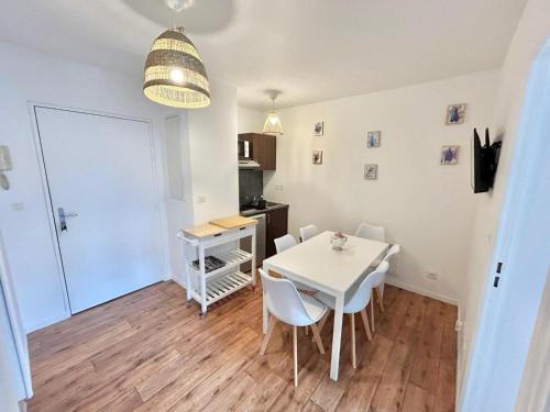 une cuisine et une salle à manger avec une table et des chaises blanches dans l'établissement Disneyland Appart Rêve enfant, à Montévrain