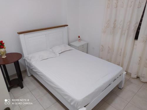 a bedroom with a white bed and a table at Chez Lopes in Praia