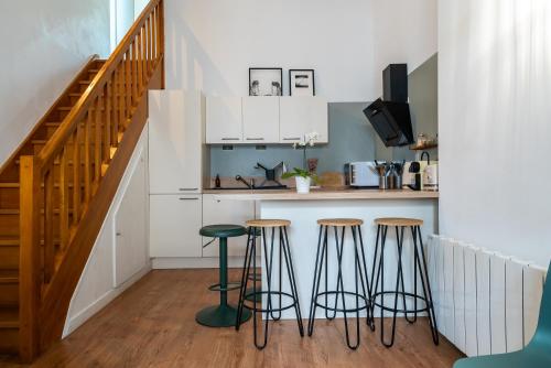 une cuisine avec un comptoir et des tabourets dans une pièce dans l'établissement Mon Appart'hôtel - Gare de Limoges - Duplex 2 Chambres - Parking en supp, à Limoges