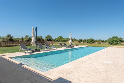 une piscine avec chaises et parasols dans une cour dans l'établissement Ferienhaus mit Privatpool für 8 Personen ca 430 qm in Felanitx, Mallorca Südostküste von Mallorca, à Felanitx