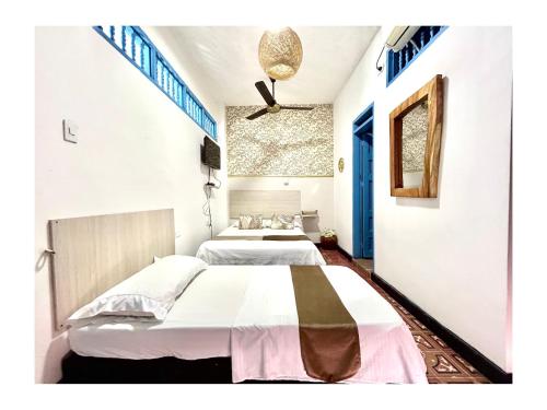 two beds in a room with white walls and blue doors at Kasaya Hotel in Santa Marta