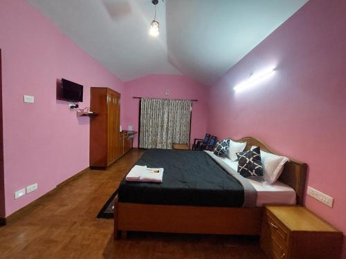 een slaapkamer met roze muren en een groot bed bij TRIOS in Ooty