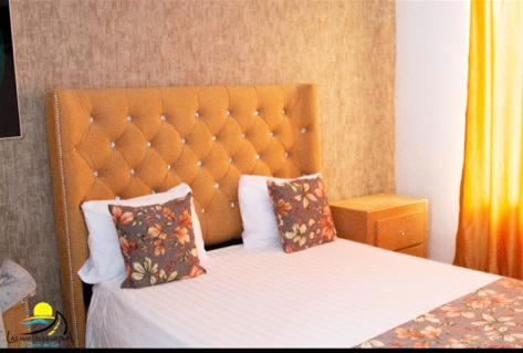 a bedroom with a bed with a orange headboard and pillows at Hotel las marias de neiba in Cerro en Medio