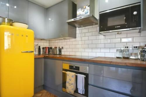 a kitchen with a yellow refrigerator in a kitchen at Modern 2 bed flat with gardens in London