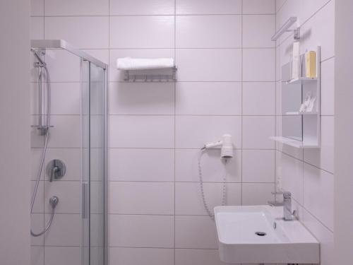 a white bathroom with a shower and a sink at Gap Hotel event & more in Langwedel