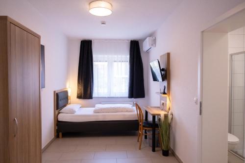 a bedroom with a bed and a desk and a window at Gap Hotel event & more in Langwedel
