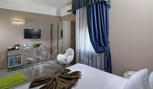 a bedroom with a bed and a chair and a television at Hotel Metropolitan in Bologna