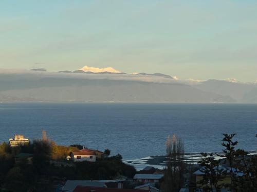 a view of the ocean with mountains in the distance at Cabaña rustica con vista al mar in Puerto Montt