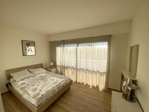 une chambre avec un lit et une grande fenêtre dans l'établissement 2P Cagnes Sur Mer- Proximité Plage, Parking, à Cagnes-sur-Mer
