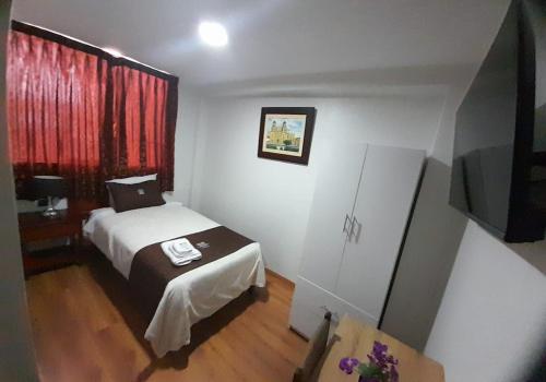a bedroom with a bed and a window with red curtains at Hotel Los Reyes in Cajamarca