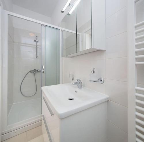 a white bathroom with a sink and a shower at Villa La Plazza in Dugopolje