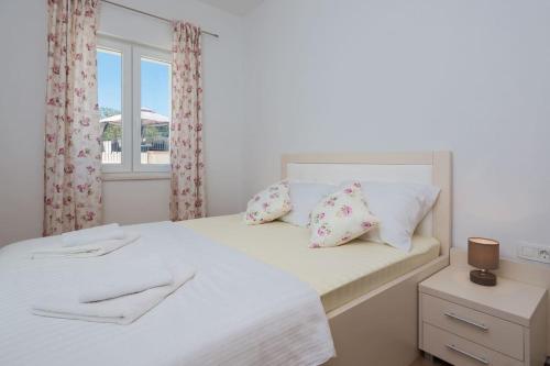 a bedroom with a white bed with pillows and a window at Villa La Plazza in Dugopolje