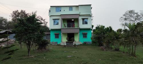 ein blaues und grünes Haus mit einem Hof in der Unterkunft India Tours Only Sundarban Natural Homestay in Mathurakhanga
