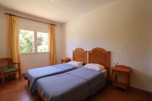 two beds in a hotel room with a window at Villa Diana in Cala'n Porter