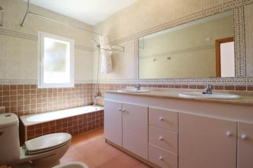 a bathroom with two sinks and a toilet and a mirror at Villa Diana in Cala'n Porter