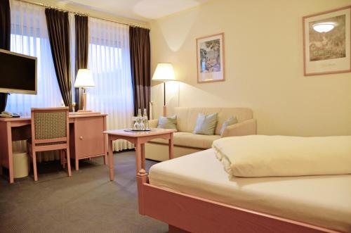 a hotel room with a bed and a couch at Hotel Gasthof Am Forsthof in Sulzbach-Rosenberg