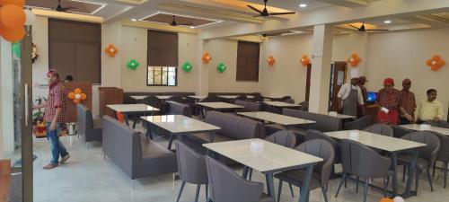 une salle à manger avec des tables, des chaises et des personnes dans l'établissement Hotel The Marion, à Nashik