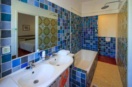 een blauw betegelde badkamer met een wastafel en een bad bij Quinta dos Amigos in Almancil