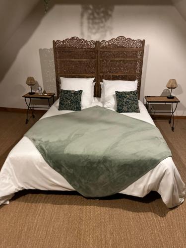 a large bed with a green blanket and pillows at Le Ginkgo in Caulnes