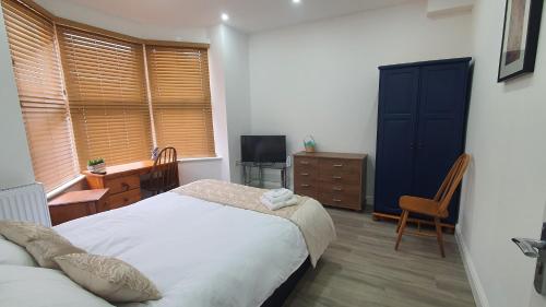 a bedroom with a bed and a desk and a television at Highfield House in Wellingborough