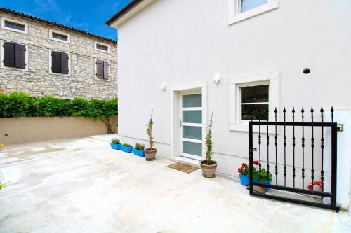 a white house with potted plants and a gate at Ferienhaus für 6 Personen ca 100 qm in Rakalj, Istrien Bucht von Raša in Rakalj