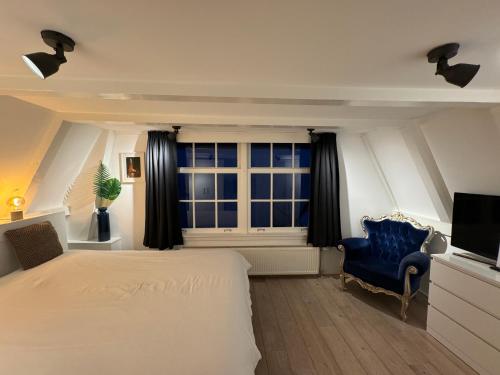 een slaapkamer met een bed en een blauwe stoel en een raam bij Nine Streets Inn in Amsterdam