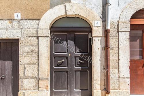 una porta nera su un edificio di pietra con due archi di Ferienwohnung für 4 Personen ca 55 qm in Andria, Adriaküste Italien Ostküste von Apulien ad Andria
