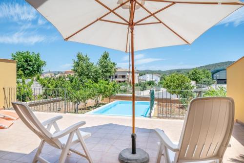 a patio with two chairs and an umbrella and a pool at Ferienhaus mit Privatpool für 7 Personen ca 272 qm in Son Carrio, Mallorca Südostküste von Mallorca in Son Carrió