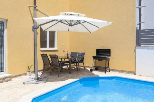 een patio met een tafel en een parasol naast een zwembad bij Villa Kostre in Loborika