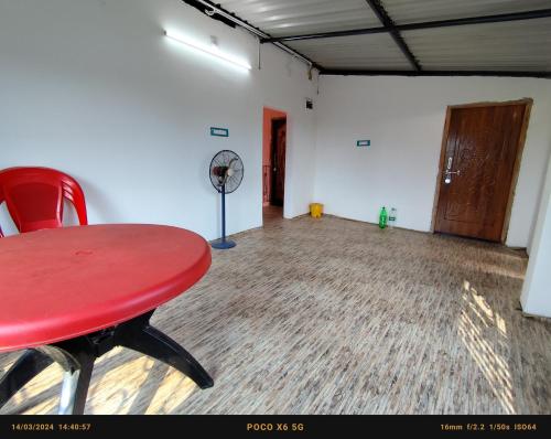 ein leeres Zimmer mit einem roten Tisch und einem Ventilator in der Unterkunft India Tours Only Sundarban Natural Homestay in Mathurakhanga