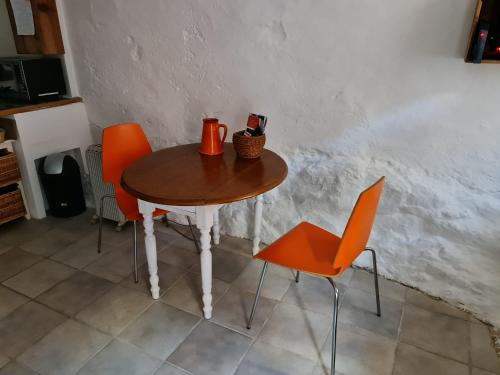 - une table en bois avec des chaises orange dans la cuisine dans l'établissement Studio du pêcheur, à Collioure