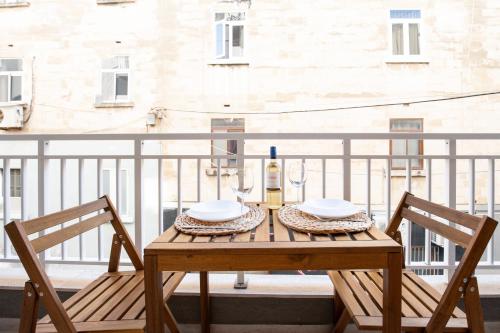 a table with a bottle of wine and two chairs on a balcony at Brand New 2 Bed 2 Bath Apartment In Sliema By The Sea in Sliema