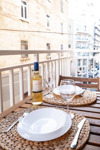 a table with a bottle of wine and glasses on a balcony at Brand New 2 Bed 2 Bath Apartment In Sliema By The Sea in Sliema
