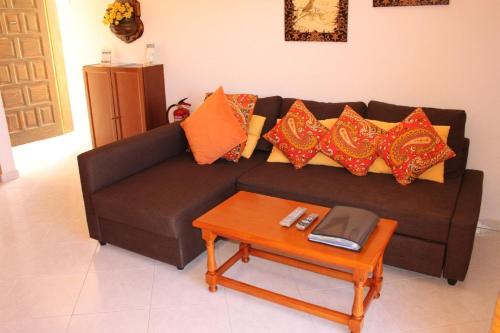 a black couch with orange pillows and a table at Liebevoll eingerichtet, ruhiges Ferienapartment mit separatem Schlafzimmer in La Pared