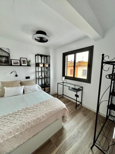 a white bedroom with a bed and a window at La Repera in Palamós