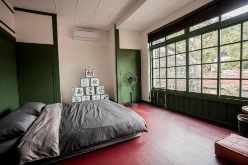 Schlafzimmer mit grünen Wänden und einem Bett mit Ventilator in der Unterkunft Xinghua Room in Kaohsiung