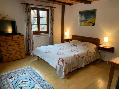 a bedroom with a bed and a dresser and a window at CHEZ SUZEL in Hunawihr