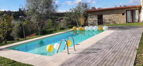 a swimming pool with chairs in front of a house at Charming house in Povoa de Lanhoso with shared pool in Póvoa de Lanhoso