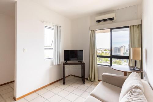 a living room with a couch and a television at Flat Metropoles Ilha do Leite by Easy Home in Recife
