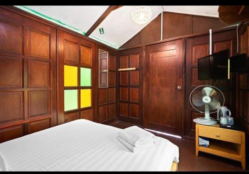 1 dormitorio con paneles de madera, 1 cama y TV en Hillside cottage tanah rata, en Tanah Rata