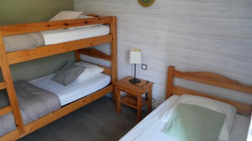 - une chambre avec 2 lits superposés et une table avec une lampe dans l'établissement Gîtes de Neyrac, appartement Rose - piscine, rivière à 100 m, vue sur les collines, à Meyras