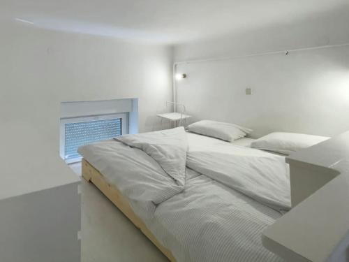 a white bedroom with a bed and a window at Lotus - Designer apt in city center in Zagreb