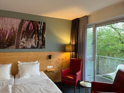 a hotel room with a bed and a chair and a window at Villavelo Twente in Ootmarsum