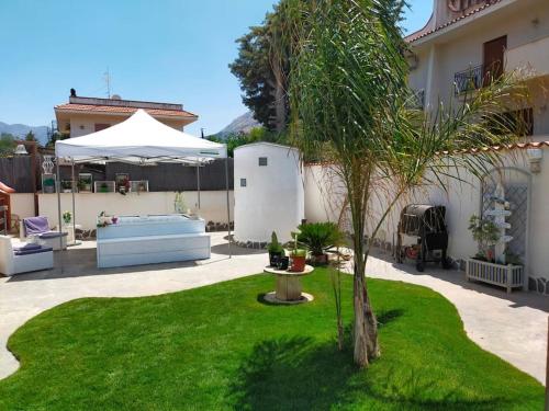 un giardino con palma e ombrellone di Villa Eco-Chic a Carini