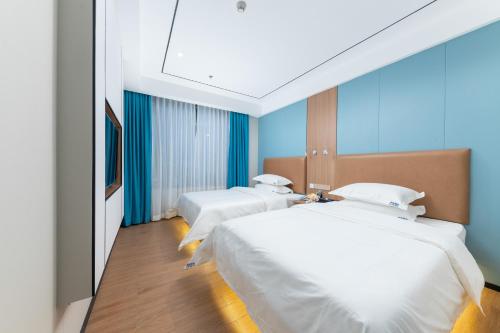 two beds in a room with blue walls at Guangzhou Haiyue Hotel in Guangzhou