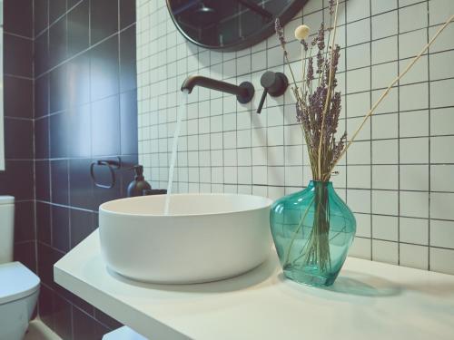 a bathroom with a sink and a vase with flowers in it at Hostal Casa Maria in Batán del Puerto
