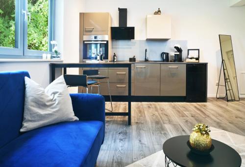 a living room with a blue couch and a kitchen at Appartement im Grünen, zentral in Biberach in Biberach an der Riß