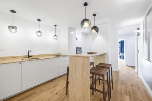 une cuisine avec des placards blancs et un îlot en bois avec des tabourets dans l'établissement Signature, à Paris