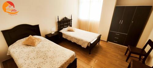 Cette petite chambre comprend deux lits et une commode. dans l'établissement NatAle Residencial - Departamento Segundo Piso con cochera, à Tacna