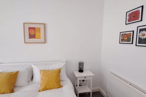 ein weißes Bett mit gelben Kissen in einem Zimmer in der Unterkunft The Tanners Cottage in Hathern